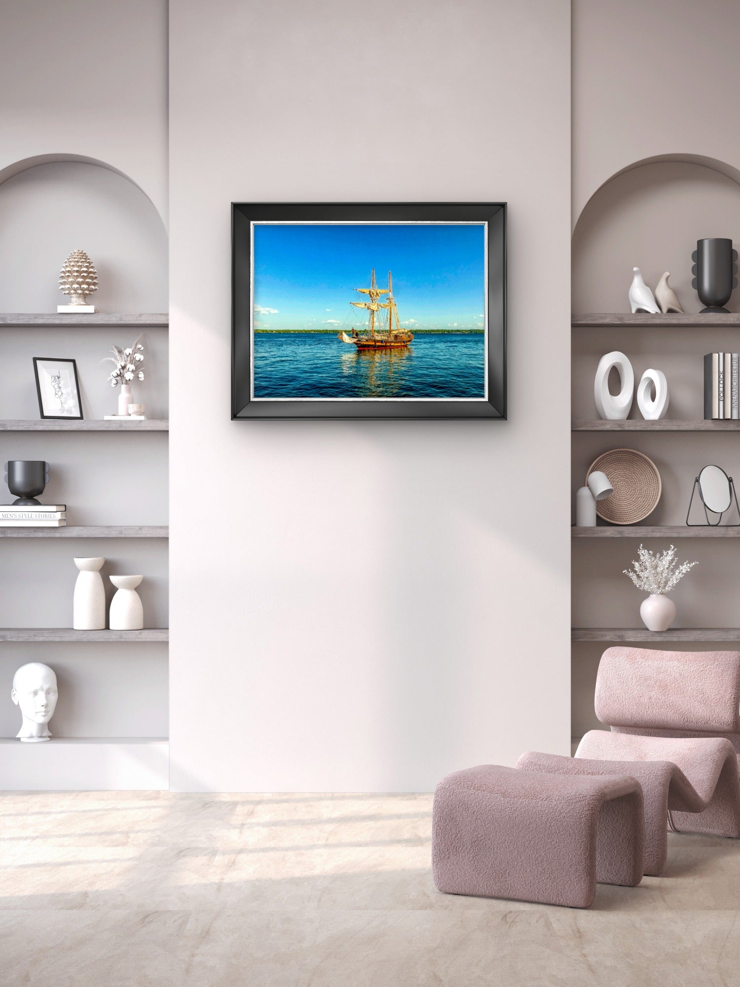 A framed art print depicting a golden sailing ship on a bright blue ocean under a clear sky, displayed on a light beige wall in a modern, styled room with built-in shelves and a pink armchair.