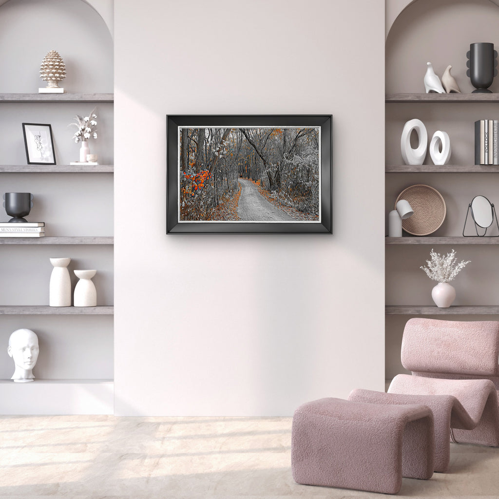 A framed art print depicting a forest path with autumn foliage, displayed on a light wall in a modern, minimalist living room setting with built-in shelves and a pink armchair.