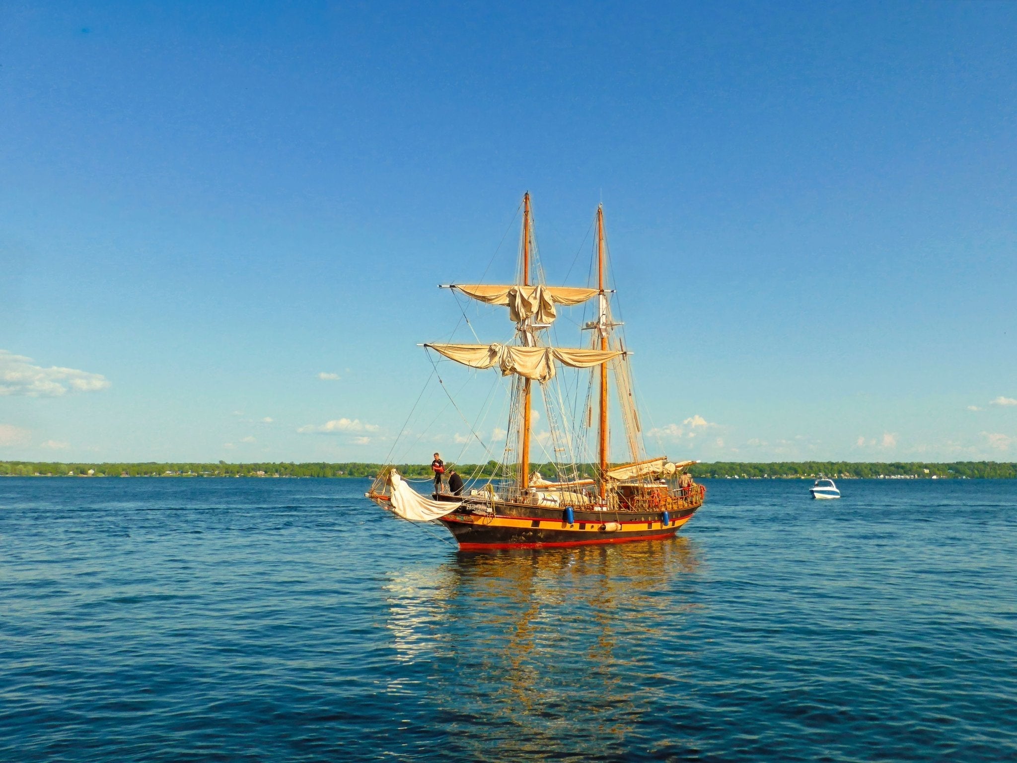 Graceful two - mast sailboat gliding beneath a flawless blue sky. - Byeutifull Art